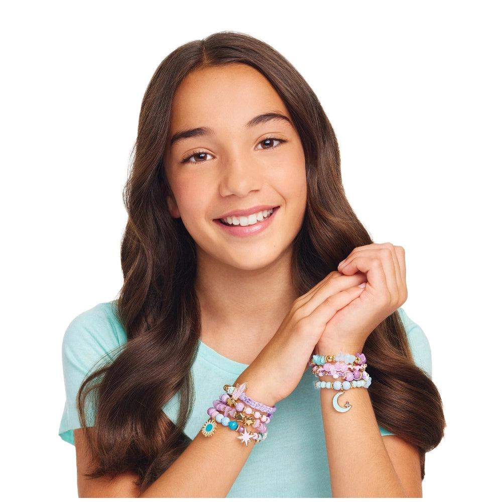 Celestial Stones bracelets adorn a young girl’s left wrist, featuring colorful designs with moon and star motifs, as she smil
