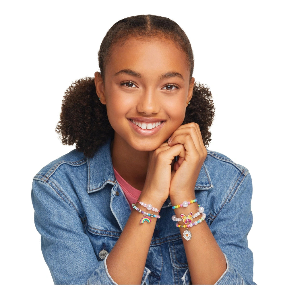 Rainbow Treasure Bracelets displayed on a smiling girl with brown curly hair, wearing a denim jacket and pink top.