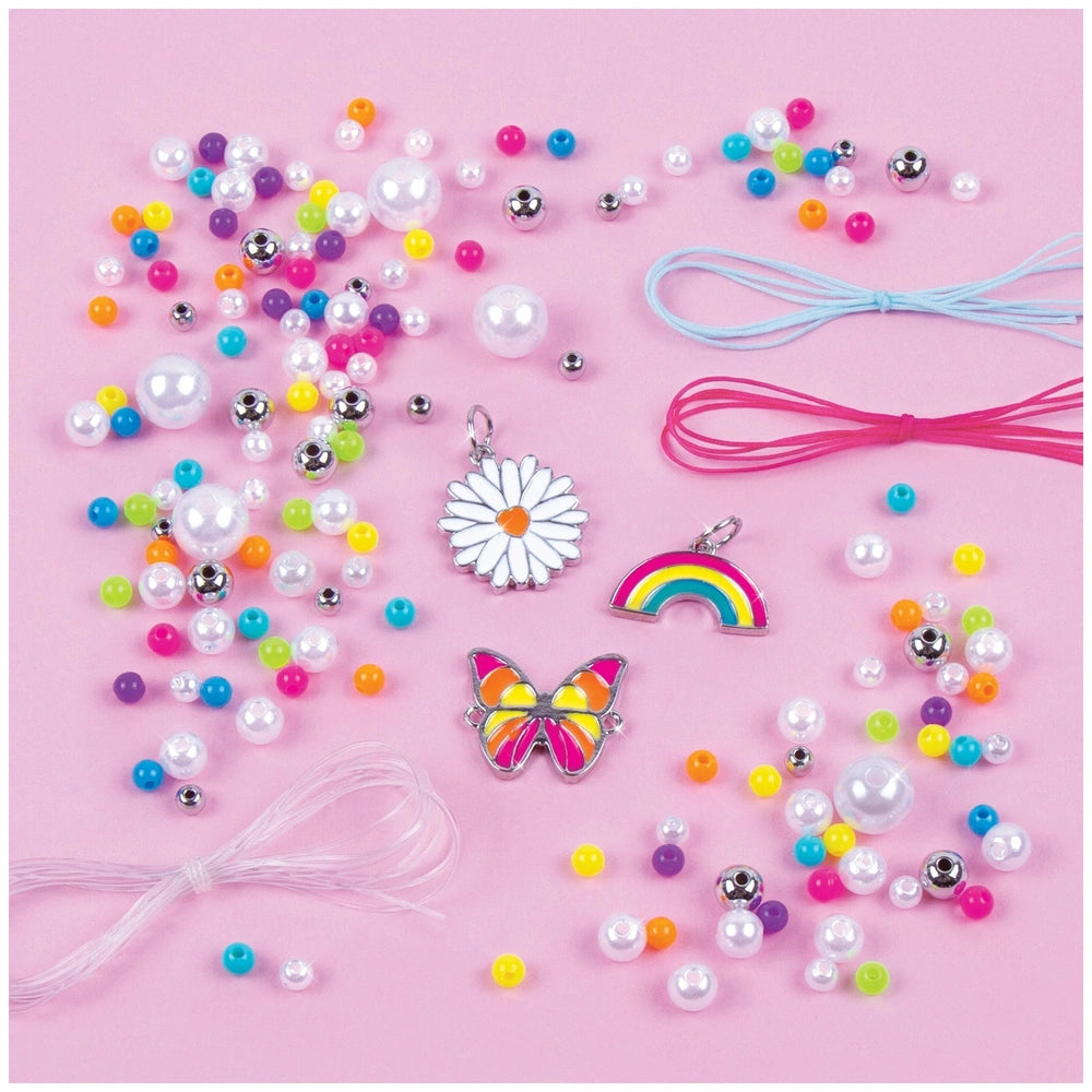 Rainbow Treasure Bracelets featuring colorful beads, metallic and glossy pendants, and pink and blue ribbons on a light pink 
