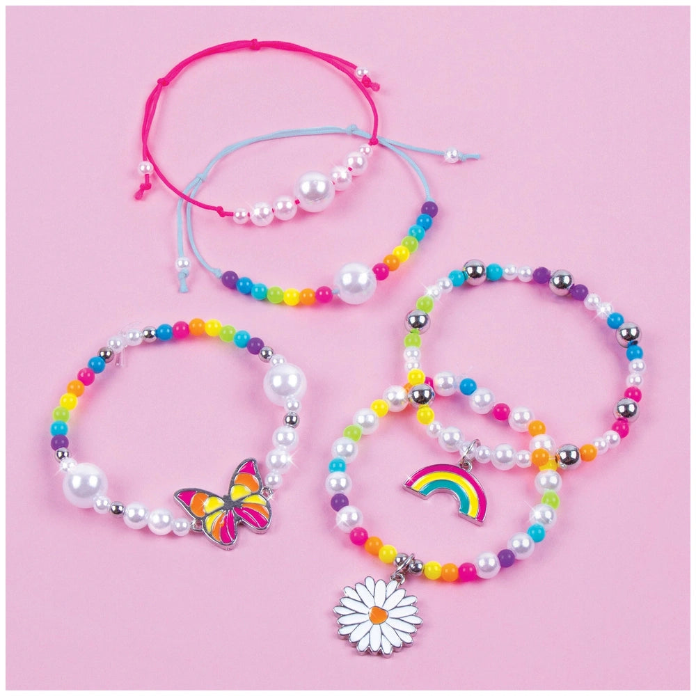 Rainbow Treasure Bracelets featuring metal, beads, pearls, and a pink hair tie with a silver clasp, arranged centrally.