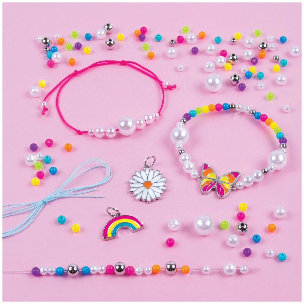 Rainbow treasure bracelet with colorful beads, accompanied by a pink hair tie and rainbow-themed accessories in a close-up vi