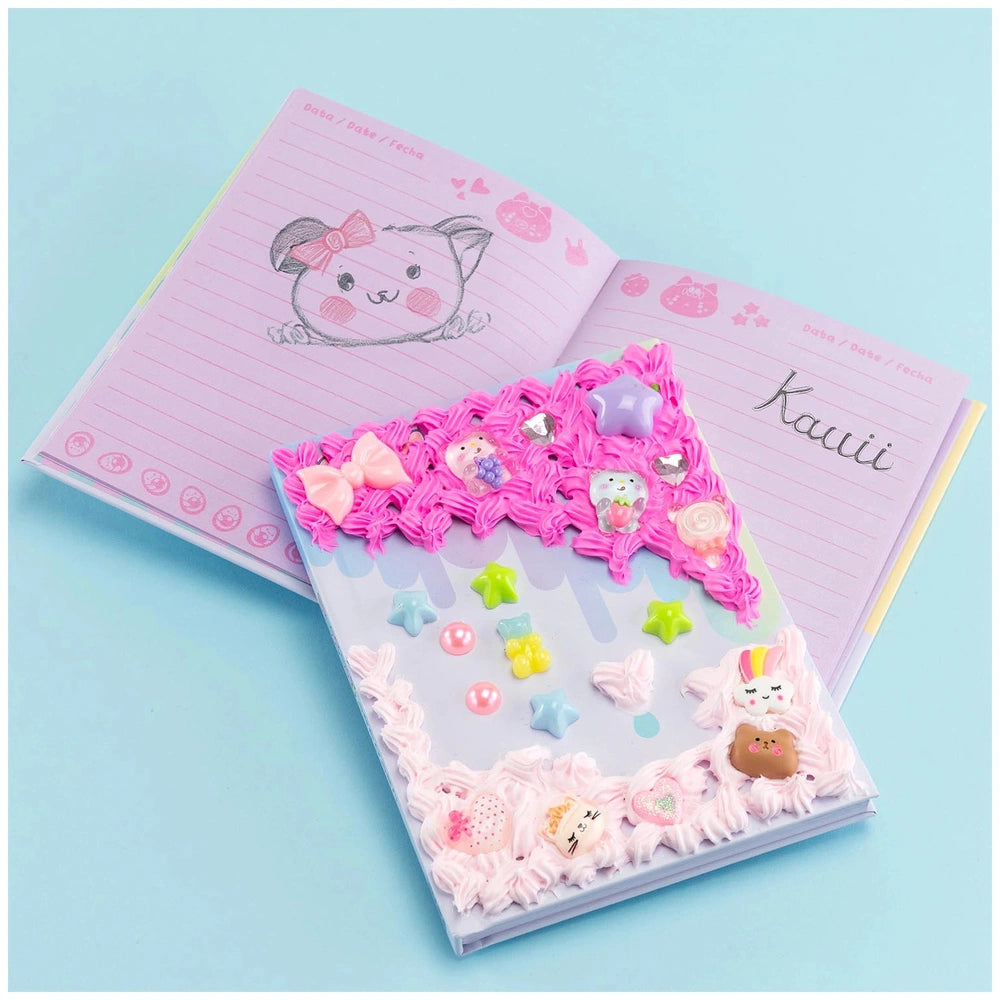 Momomi Decoden Kawaii Artist Creamy Diary kit features a matte pink cover with blue borders and glossy pink-bordered pages.