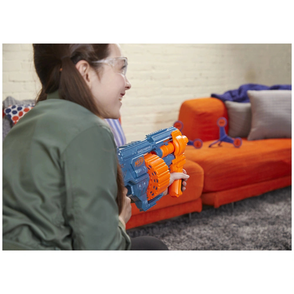 Nerf Elite 2.0 Shockwave RD-15 Blaster held by a woman in a green shirt, with an orange couch and gray pillows in the backgro