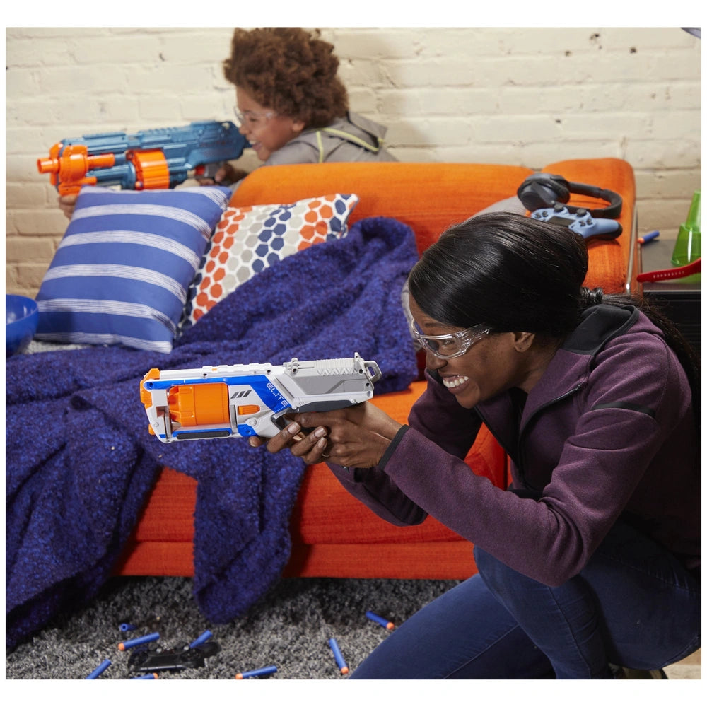 Nerf Elite 2.0 Shockwave RD-15 Blaster on an orange couch with two people, blue blanket, and gray brick wall in the backgroun