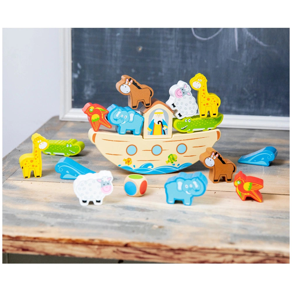New Classic Toys Balance Game features colorful animal-shaped plastic toys arranged in a boat on a brown wooden table.