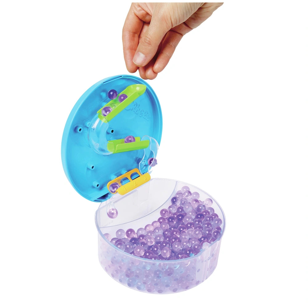 Orbeez Water Beads Surprise Activity Orb Set in a hand, dispensing small purple beads from a blue and yellow toy.