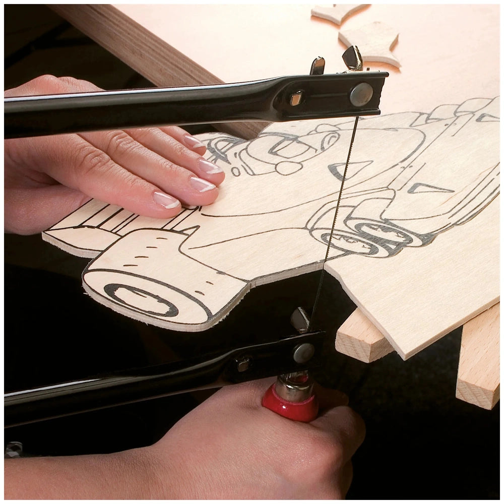 Hands using a fretsaw on a wooden template with black farm-themed outlines; part of Barnyard II arts and crafts set.