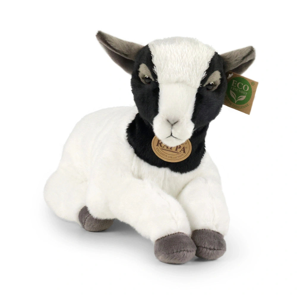 Plush goat with a white body and black markings, sitting upright on a smooth, light-colored surface.