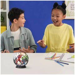 Ravensburger 3D puzzle ball featuring Marvel Avengers is displayed on a table with two engaged children smiling.