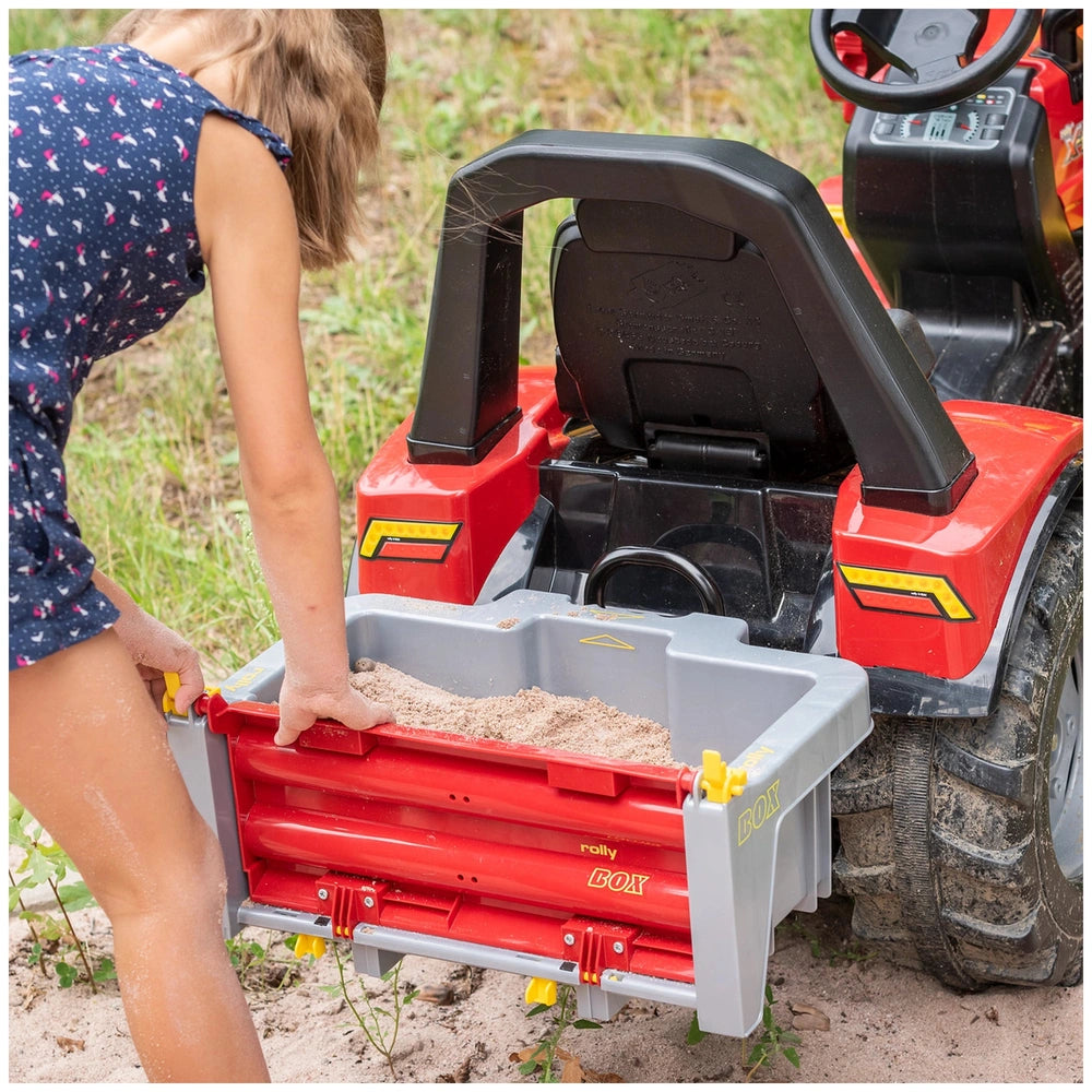 Rollybox John Deere four-wheeler in red and black with open storage compartment, grass background, and person interacting.