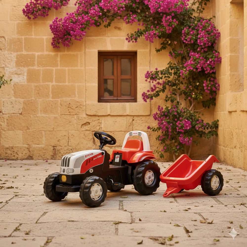 Rollykid Steyr 6165 Cvt tractor and trailer in an outdoor setting with a stone wall and pink flowers.