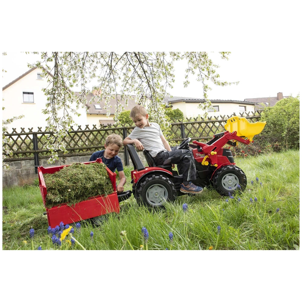 Rollymega red trailer is featured with two boys playing on a lawn mower in a grassy outdoor setting with a house in the backg