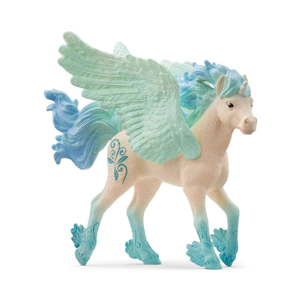 A glossy white unicorn foal figurine with blue accents on its mane, tail, and hooves stands on a white surface.