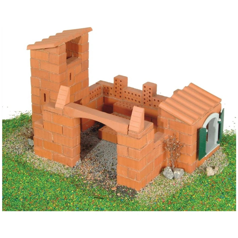 Teifoc Castle-House model features red brick walls, a green roof, and a grassy base with scattered rocks.