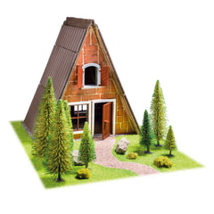 Teifoc Finnish hut model features a brown brick house with a sloped roof, surrounded by green grass, trees, and rocks.