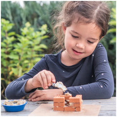 Teifoc small family home set features a young girl in a blue shirt engaged with a brown brick structure at a wooden table.