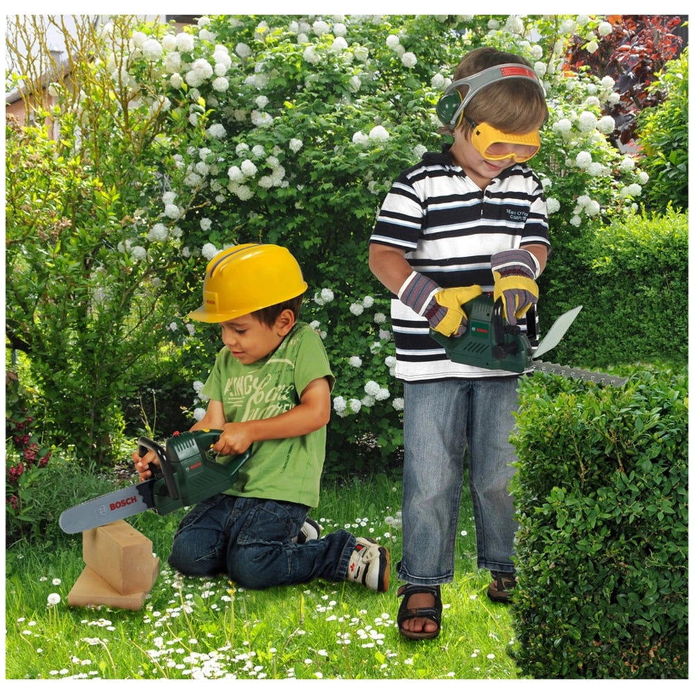 Theo Klein Bosch hedge trimmer with two children in hard hats and safety goggles, playing in a garden setting.