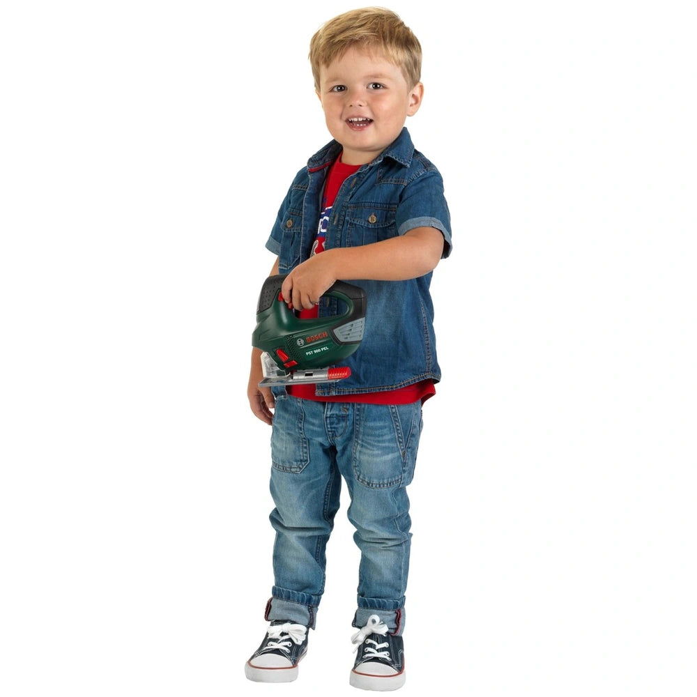 Theo Klein Bosch jigsaw toy held by a smiling boy in a denim jacket, red t-shirt, blue jeans, and white sneakers.